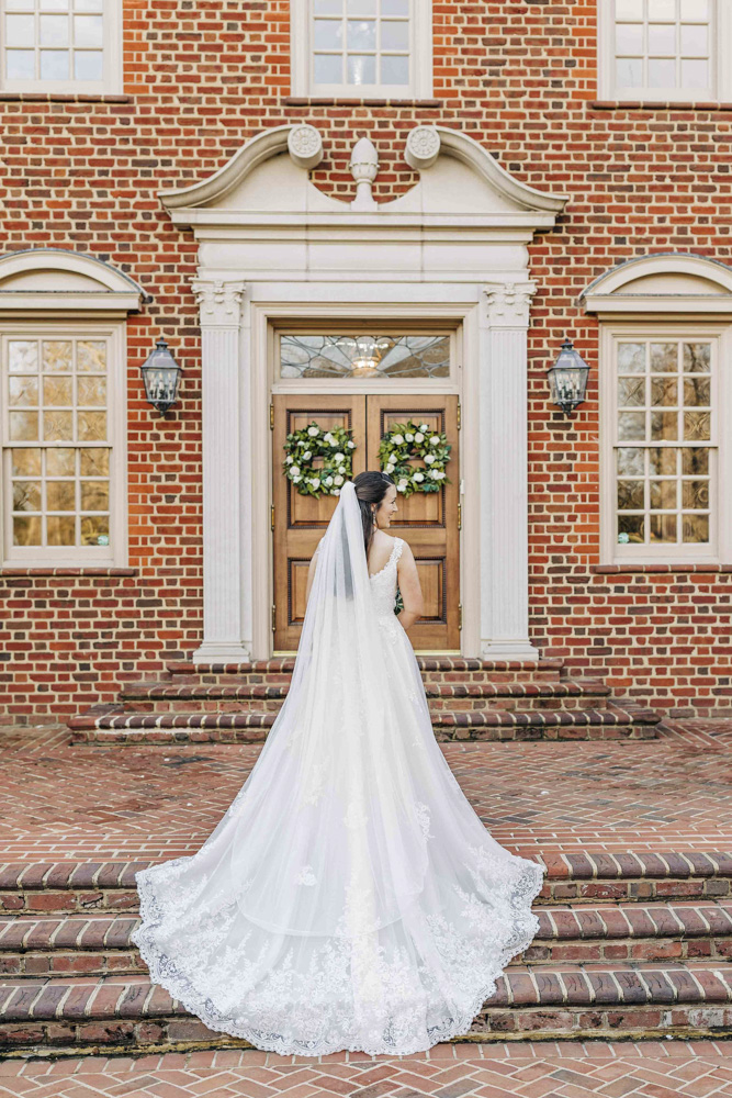 bride in front of wooden door of brick building at Bridal Portraits at The Estate at River Run