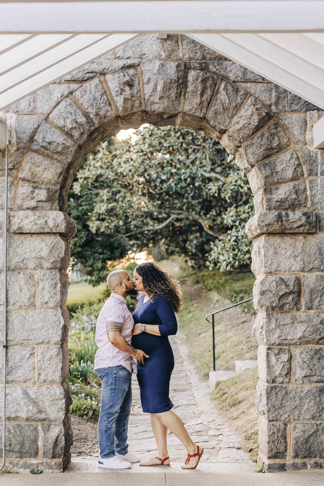 pregnant couple poses for maternity photos at Maymont Park under archway